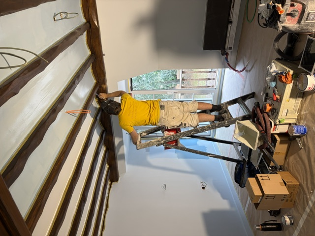 Schilder op een ladder werkt aan een houten balkenplafond